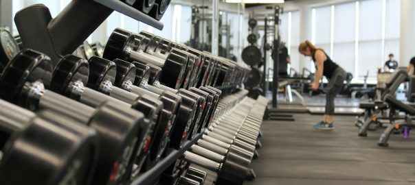 woman standing surrounded by exercise equipment